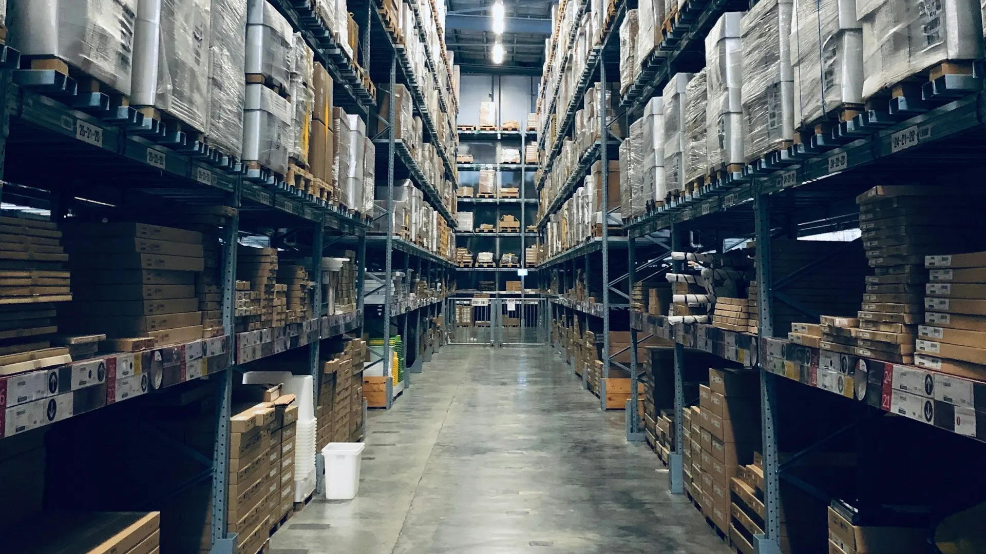 A long warehouse aisle with tall shelves of boxed stock.